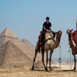 Un turista se toma una selfie mientras monta en camello en la Necrópolis de las Pirámides de Giza, en las afueras de Giza, Egipto. | Foto:Jewel Samad / AFP