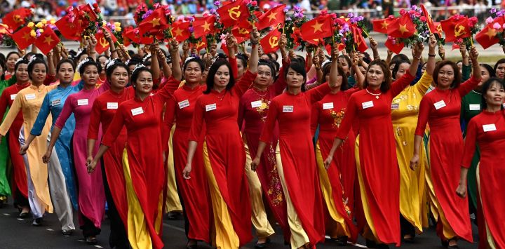 Las mujeres ondean banderas durante las celebraciones oficiales del 70º aniversario de la victoria de Dien Bien Phu en 1954 sobre las fuerzas coloniales francesas en un estadio de la ciudad de Dien Bien Phu, Vietnam.