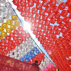 Un trabajador del templo coloca tarjetas con los deseos de los seguidores budistas en linternas de loto en el templo Jogyesa en Seúl, antes de las celebraciones que marcan el cumpleaños de Buda el 15 de mayo. | Foto:Jung Yeon-je / AFP
