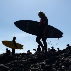 Los surfistas se dirigen al mar para participar en una ceremonia en honor a dos surfistas australianos y un estadounidense que desaparecieron la semana pasada durante un viaje de surf en la playa de San Miguel en Ensenada, estado de Baja California, México. | Foto:Guillermo Arias/AFP