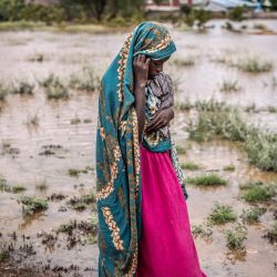 Una mujer que ha sido desplazada de su casa debido a las fuertes inundaciones se encuentra junto a una zona inundada junto a un campamento para personas desplazadas en Garissa, Kenia. | Foto:LUIS TATO/AFP