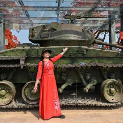 Una mujer vietnamita con un vestido tradicional posa para fotos junto a un tanque francés en la cima del sitio histórico de la batalla de la colina A1 en la ciudad de Dien Bien Phu. | Foto:NHAC NGUYEN / AFP