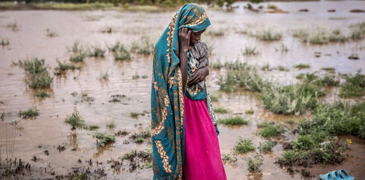 Una mujer que ha sido desplazada de su casa debido a las fuertes inundaciones se encuentra junto a una zona inundada junto a un campamento para personas desplazadas en Garissa, Kenia.