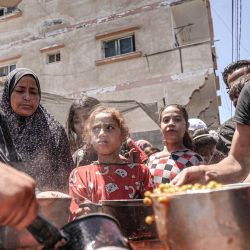 La gente recibe porciones de comida de una olla grande en una cocina pública en Deir el-Balah, en el centro de la Franja de Gaza,, en medio del conflicto en curso en el territorio palestino entre Israel y Hamás. | Foto:AFP