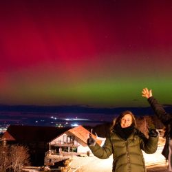 Las mujeres posan para fotografías mientras la Aurora Austral, también conocida como Luces del Sur, brilla en el horizonte vista desde Ushuaia, Tierra del Fuego, Argentina. La tormenta solar más poderosa en más de dos décadas golpeó la Tierra, provocando espectáculos de luces celestiales desde Tasmania hasta Gran Bretaña, y amenazando con posibles interrupciones en los satélites y las redes eléctricas mientras persista. | Foto:ALEXIS DELELISI / AFP
