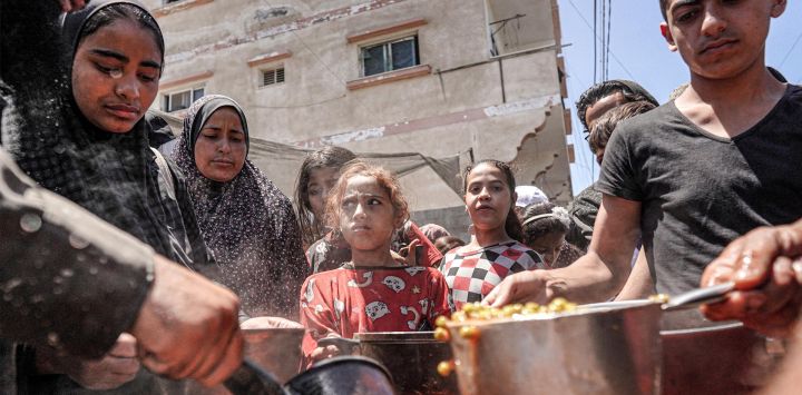 La gente recibe porciones de comida de una olla grande en una cocina pública en Deir el-Balah, en el centro de la Franja de Gaza,, en medio del conflicto en curso en el territorio palestino entre Israel y Hamás.