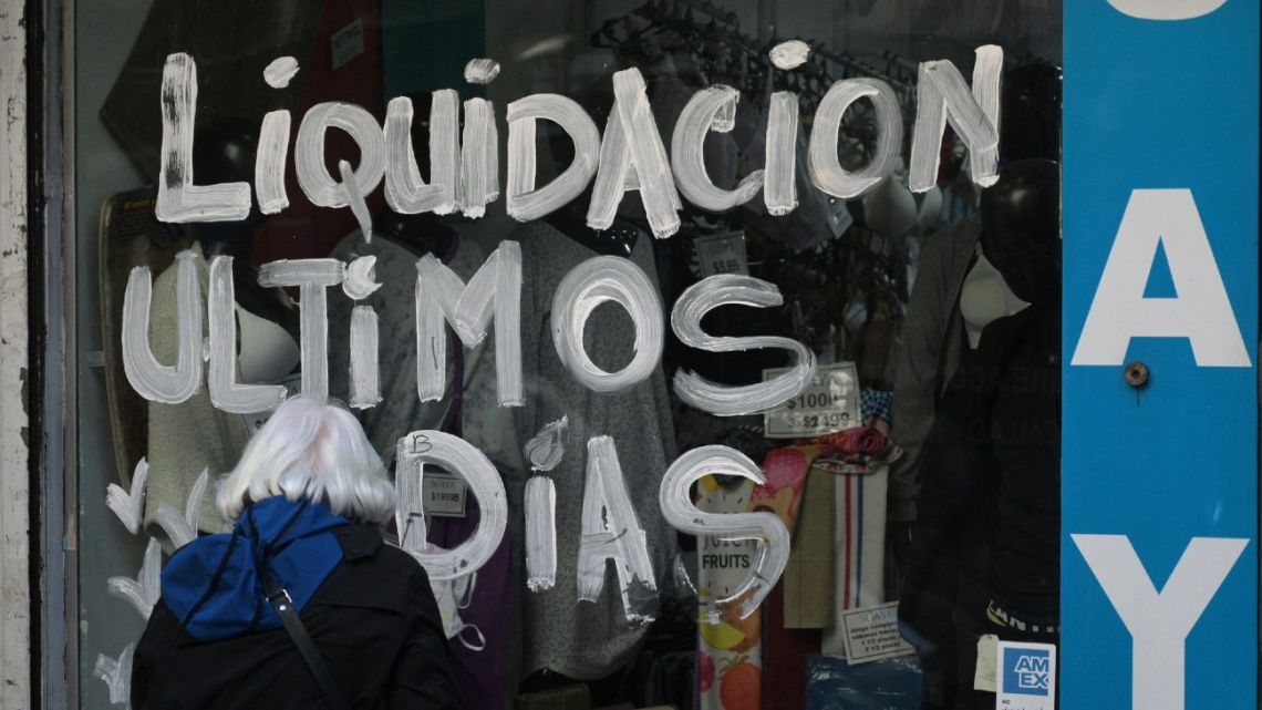 A woman looks at the window of a clothing store that reads 'Clearance Last Days' in Buenos Aires on May 14, 2024, on the day of the announcement of April's inflation index. 