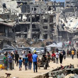 La gente pasa junto a edificios destruidos a lo largo de una calle en Khan Yunis, en el sur de la Franja de Gaza, en medio del conflicto en curso en el territorio palestino entre Israel y Hamás. | Foto:AFP