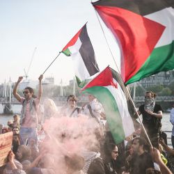 Los manifestantes ondean banderas palestinas y blanden una bengala de humo durante una manifestación pro-palestina en el puente de Waterloo, en Londres, organizada por la asociación Youth Demand y pidiendo un embargo de armas bidireccional a Israel. | Foto:HENRY NICHOLLS / AFP