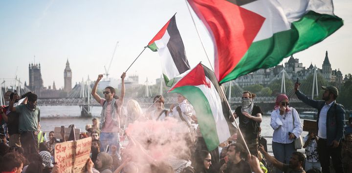 Los manifestantes ondean banderas palestinas y blanden una bengala de humo durante una manifestación pro-palestina en el puente de Waterloo, en Londres, organizada por la asociación Youth Demand y pidiendo un embargo de armas bidireccional a Israel.