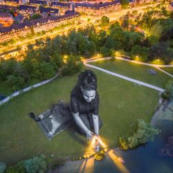 Esta fotografía aérea tomada por el artista francés Guillaume Legros, también conocido como “Saype”,  muestra una obra de arte efímera gigante de 4.500 metros cuadrados titulada “Sueños brillantes” pintada por Saype en el Irchelpark de Zurich. Realizada con pintura ecológica, la obra de arte efímera muestra a una niña rodeada de varios símbolos que evocan el rescate en el mar, en apoyo a la ONG humanitaria de rescate marítimo "SOS Mediterranee Suiza". | Foto:Guillaume Legros / AFP