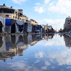 Palestinos desplazados caminan alrededor de un charco frente a edificios y tiendas de campaña destruidos en Khan Yunis, en el sur de la Franja de Gaza, en medio del conflicto en curso entre Israel y el grupo militante Hamás. | Foto:AFP