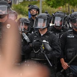 Un manifestante pro palestino hace un signo de paz frente a la policía mientras limpian un campamento después de que los estudiantes ocuparan la sala de conferencias de Ciencias Físicas de la Universidad de California, Irvine, en Irvine, California. | Foto:Patrick T. Fallón / AFP