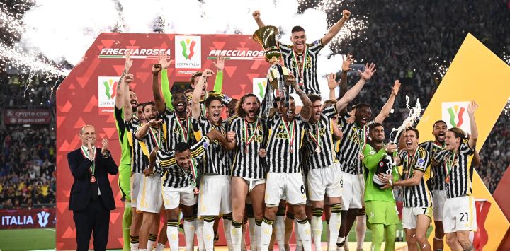 El defensor brasileño de la Juventus Danilo sostiene el trofeo mientras los jugadores de la Juventus celebran después de ganar la final de la Copa de Italia entre Atalanta y Juventus en el estadio olímpico de Roma.