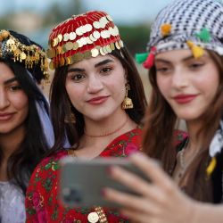 Jóvenes kurdas con vestidos tradicionales se toman una selfie grupal durante un festival de disfraces en la ciudad de Zakho, en el norte de Irak, cerca de la frontera con Turquía. | Foto:Ismael Adnan/AFP