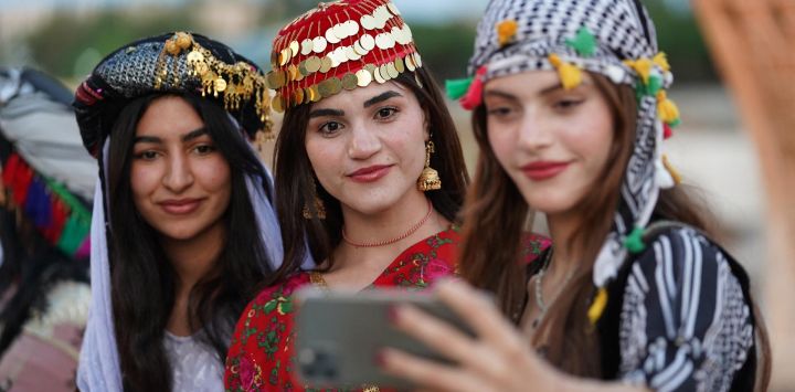 Jóvenes kurdas con vestidos tradicionales se toman una selfie grupal durante un festival de disfraces en la ciudad de Zakho, en el norte de Irak, cerca de la frontera con Turquía.