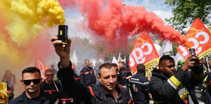 Los bomberos sostienen bombas de humo mientras asisten a una jornada de protesta y huelga a nivel nacional convocada por todos los sindicatos de bomberos, para pedir un aumento del bono de los bomberos, que premia su valentía y dedicación, un beneficio económico para los bomberos movilizados durante los Juegos Olímpicos de París 2024.