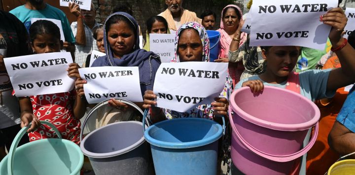 Los residentes sostienen carteles que dicen "Sin agua, no hay voto" y baldes para protestar por el suministro inadecuado de agua en Amritsar, India.