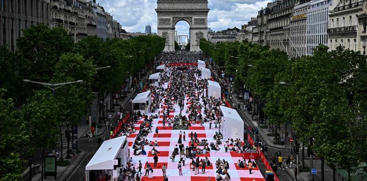 La gente participa en un picnic gigante al aire libre en la avenida de los Campos Elíseos de París. Unas 4.000 personas fueron seleccionadas para almorzar sobre una alfombra "la alfombra del mundo". Foto JULIEN DE ROSA / AFP