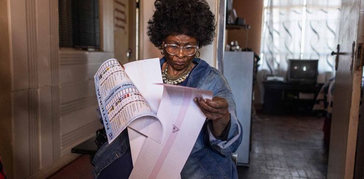 La votante especial de edad avanzada Thelma Thembeka Dingaan, de 65 años, revisa sus papeletas de voto en su casa de Yeoville, Johannesburgo. Foto Michele Spatari / AFP
