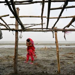 Una mujer lleva a un niño mientras pasa por una tienda dañada después de que el ciclón Remal tocara tierra en Patuakhali. Foto Munir Uz Zaman / AFP | Foto:AFP