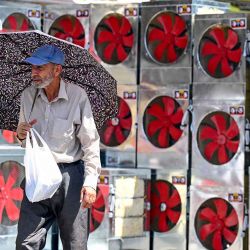 Un cliente que lleva un paraguas visita una tienda que vende refrigeradores de aire en una calurosa tarde de verano, en un mercado en Rawalpindi. Foto de Farooq NAEEM / AFP | Foto:AFP