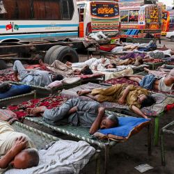 Los conductores duermen en una estación de autobuses en un caluroso día de verano en Lahore, Pakistán, en medio de una fuerte ola de calor. | Foto:Arif Ali / AFP