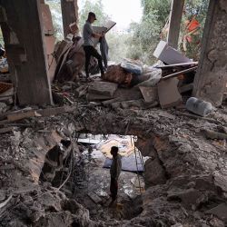 Los palestinos inspeccionan los daños sufridos por una casa después de que fuera alcanzada por un ataque israelí en el campamento de al-Bureij, en el centro de la Franja de Gaza, en medio del conflicto en curso entre Israel y el grupo militante palestino Hamas. | Foto:Bashar Taleb / AFP
