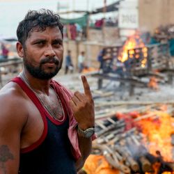 Ganga Ram Chowdhary, un miembro de la comunidad Dom que trabaja en un campo de cremación, muestra su dedo entintado después de emitir su voto durante la séptima y última fase de la votación en las elecciones generales de la India, mientras arden piras funerarias en Harishchandra ghat a orillas del río Ganges en Varanasi. | Foto:NIHARIKA KULKARNI / AFP
