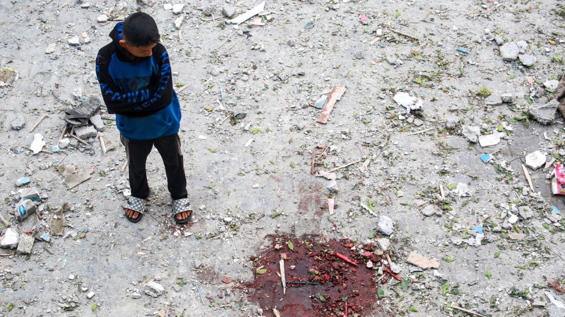 A Palestinian boy looks at a pool of blood at a UN-school housing displaced people that was hit during Israeli bombardment in Nuseirat, in the central Gaza Strip, on June 6, 2024, amid the ongoing conflict between Israel and the Palestinian Hamas militant group. 