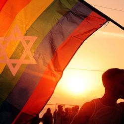 Dos participantes se besan mientras sostienen una bandera arcoíris de orgullo con una estrella de David en Tel Aviv durante la "Asamblea Orgullo y Esperanza" coordinada con el Foro de Familias Rehenes que pide el regreso de los rehenes cautivos en la Franja de Gaza desde el Ataques del 7 de octubre, en medio del conflicto en curso en el territorio palestino entre Israel y Hamás. | Foto:JACK GUEZ / AFP