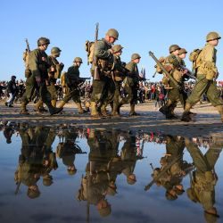 Entusiastas vestidos con réplicas de atuendos militares de la Segunda Guerra Mundial del ejército de EE. UU. desfilan a lo largo de Utah Beach como parte de las conmemoraciones del "Día D" que marca el 80 aniversario del desembarco aliado de la Segunda Guerra Mundial en Normandía. | Foto:LOIC VENANCE / AFP