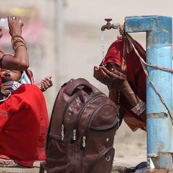 Las mujeres sacian su sed con agua del grifo en una calurosa tarde de verano durante la ola de calor en Prayagraj, India. | Foto:ANIL SHAKYA / AFP