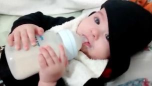Bebé tomando leche en mamadera de plástico 20240610