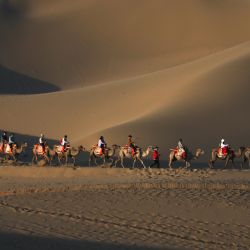 Imagen de turistas montados en camello en el Mingshashan y el Lago de Creciente, un punto escénico de oasis en el desierto de Gobi, en Dunhuang, en el noroeste de China. | Foto:Xinhua/Zhang Xiaoliang