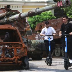 Jóvenes viajan en scooters junto al equipo militar ruso destruido en la plaza Mykhailivska en el centro de Kiev, en medio de la invasión rusa en Ucrania. | Foto:Anatolii Stepanov / AFP