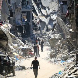 Hombres palestinos caminan por una calle estrecha pasando por edificios destruidos en Khan Yunis, en el sur de la Franja de Gaza, en medio del conflicto en curso entre Israel y el grupo militante palestino Hamas. | Foto:Eyad Baba / AFP