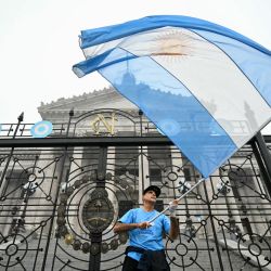 Un manifestante ondea la bandera argentina frente al Congreso Nacional en Buenos Aires. Los senadores argentinos están discutiendo un paquete de reformas clave para el presidente de extrema derecha Javier Milei, en una sesión marcada por huelgas y manifestaciones frente del Congreso. | Foto:Luis Robayo/AFP
