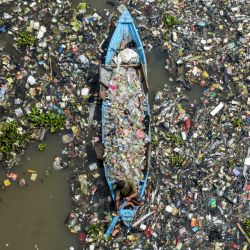 Un hombre en un barco recoge plásticos reciclables del río Citarum, muy contaminado, en Batujajar, Bandung, Java Occidental, Indonesia. | Foto:TIMUR MATAHARI / AFP