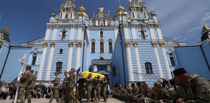 Los dolientes se arrodillan mientras los militares ucranianos llevan el ataúd del militar ucraniano, el fotógrafo Arsen Fedosenko, quien fue asesinado en la región de Kharkiv, en el Monasterio de las Cúpulas Doradas de San Miguel en Kiev, en medio de la invasión rusa en Ucrania.