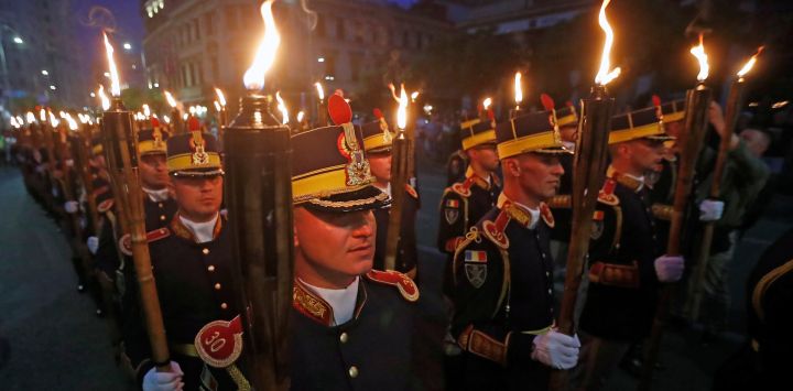 Soldados rumanos sostienen antorchas durante una marcha para conmemorar el Día de los Héroes, en el centro de Bucarest, Rumania.