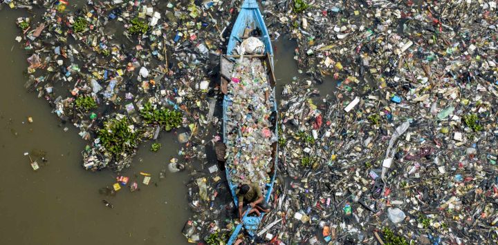 Un hombre en un barco recoge plásticos reciclables del río Citarum, muy contaminado, en Batujajar, Bandung, Java Occidental, Indonesia.