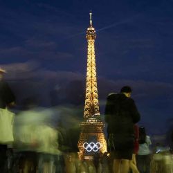 La gente se para frente a los anillos olímpicos que adornan la Torre Eiffel en París el 22 de junio de 2024, antes de los próximos Juegos Olímpicos de París 2024. (Foto de Stefano RELLANDINI / AFP) | Foto:AFP