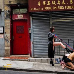 Una mujer vestida de dominatriz posa para unas fotografías (no se ve al fotógrafo) con dos hombres interpretando a animales en el barrio de Chinatown de Manhattan, Nueva York, el 23 de junio de 2024. (Foto de Charly TRIBALLEAU / AFP) | Foto:AFP