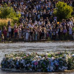 Personas paradas a orillas del río Vístula en Varsovia, Polonia, observan cómo una enorme corona flota en el agua durante el llamado Wianki nad Wis?? (Coronas sobre el Vístula) el 22 de junio de 2024. Las celebraciones están relacionadas con las tradiciones y rituales de la Noche de Kupala en el solsticio de verano, como hacer coronas de flores del campo y arrojarlas al río como portadoras de felicidad y suerte. (Foto de Wojtek Radwanski / AFP)   | Foto:AFP