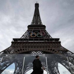 Una persona pasa junto a la Torre Eiffel, decorada con los anillos olímpicos para los próximos Juegos Olímpicos de París 2024, en París el 14 de junio de 2024. (Foto de Valentine CHAPUIS / AFP) | Foto:AFP
