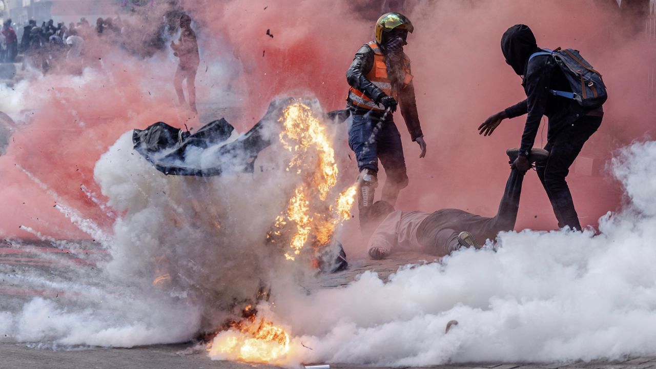 Un bote de gas lacrimógeno explota mientras los manifestantes intentan ayudar a los heridos frente al Parlamento de Kenia durante una huelga nacional para protestar contra los aumentos de impuestos y el Proyecto de Ley de Finanzas 2024 en el centro de Nairobi. | Foto:LUIS TATO/AFP