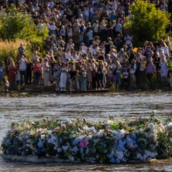 Personas de pie a orillas del río Vístula en Varsovia, Polonia, observan cómo una enorme corona flota en el agua durante el llamado Coronas sobre el Vístula. Las celebraciones están relacionadas con las tradiciones y rituales de la Noche de Kupala en el solsticio de verano, como hacer coronas de flores del campo y arrojarlas al río como portadoras de felicidad y suerte. | Foto:Wojtek Radwanski / AFP
