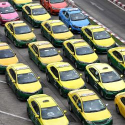 Un conductor pasa mientras los taxis esperan en cola en el aeropuerto internacional Don Mueang de Bangkok, Tailandia. | Foto:MANAN VATSYAYANA / AFP