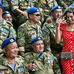 Una mujer posa para una fotografía con los veteranos de Kirguistán junto a un monumento a los soldados soviéticos muertos en acción en Afganistán durante la invasión soviética de 1979-1989, marcando el Día anual de los Veteranos de Combate en el Parque Memorial de la Guerra de Poklonnaya Hill en Moscú. | Foto:Alexander Nemenov / AFP